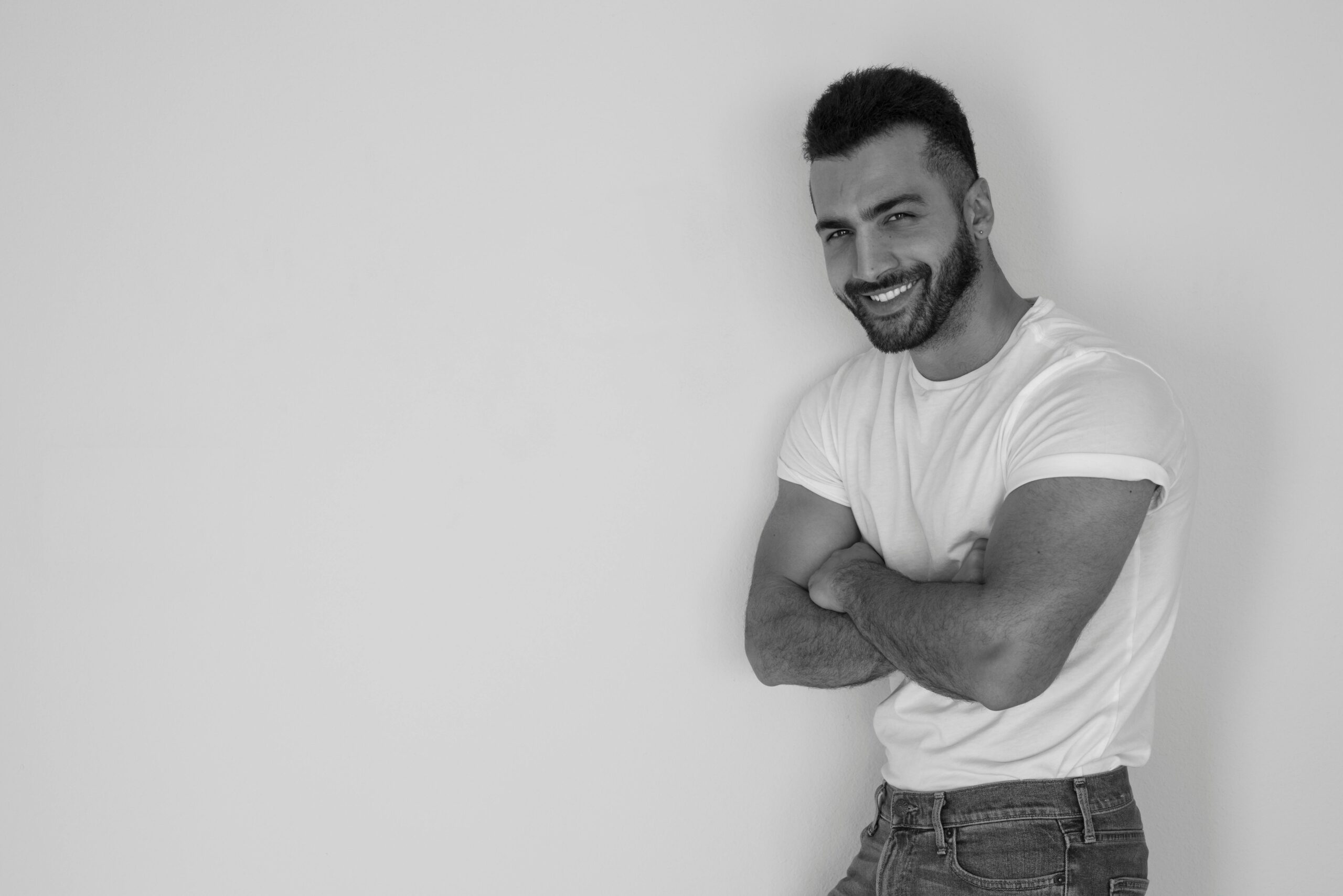 pexels-photo-735551-735551 Monochrome portrait of a stylish man with arms crossed, exuding confidence in a studio setting.